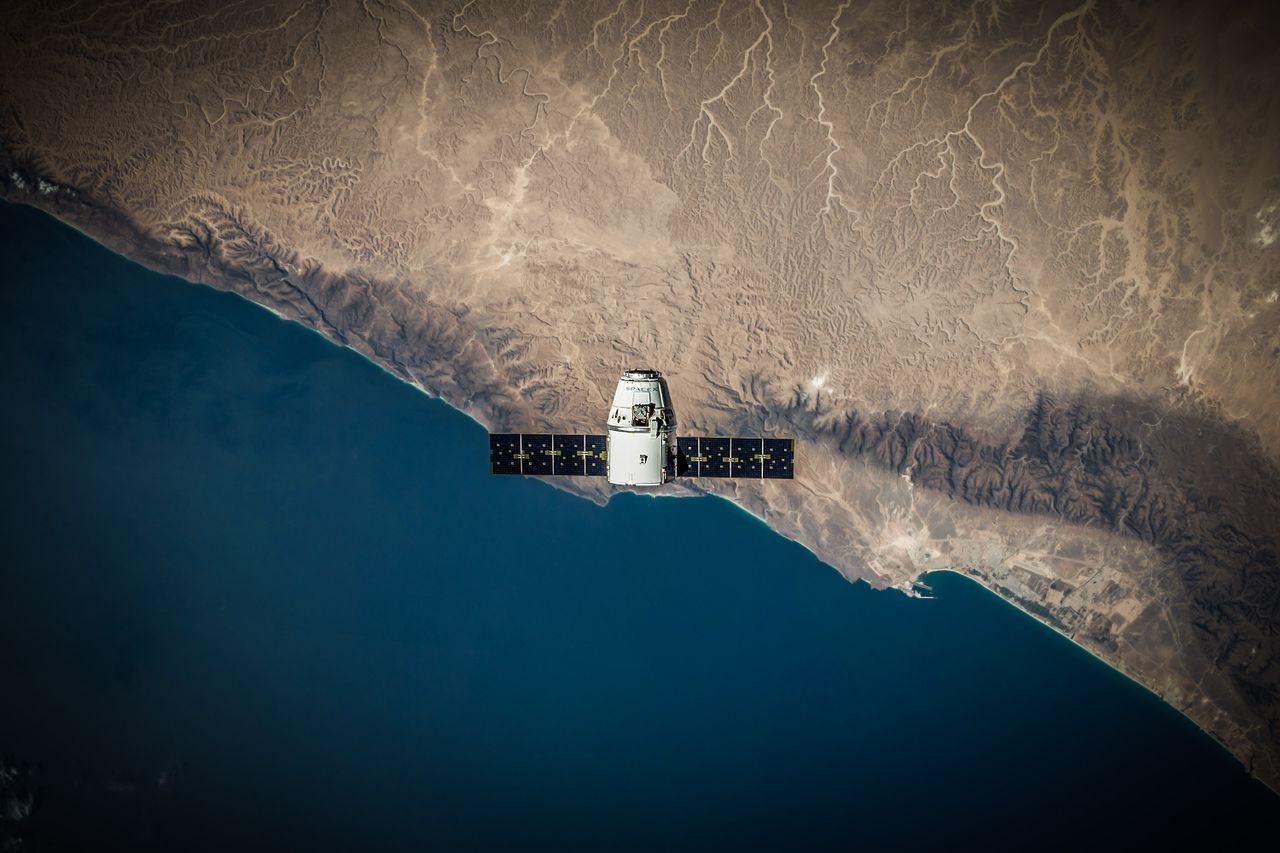 about-us-02 A satellite hovering above Earth's coastline, captured from space.